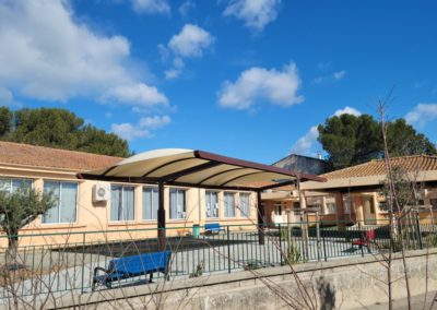 Vue sur l'école et le préau de couleur ivoire installé dans la cour Oasis.