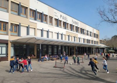 Enfants jouant dans la cour et sous le préau de l'école.