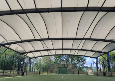 Vue sur le dessous du préau sportif dont la toile tendue est de couleur blanche.