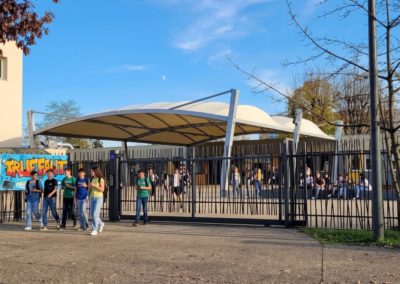 Collégiens qui discutent devant le collège et sous le préau de couleur beige et accolé au collège.